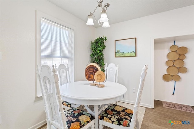 dining space featuring light wood finished floors, a chandelier, and baseboards