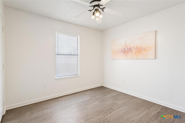 empty room featuring ceiling fan, baseboards, a textured ceiling, and wood finished floors