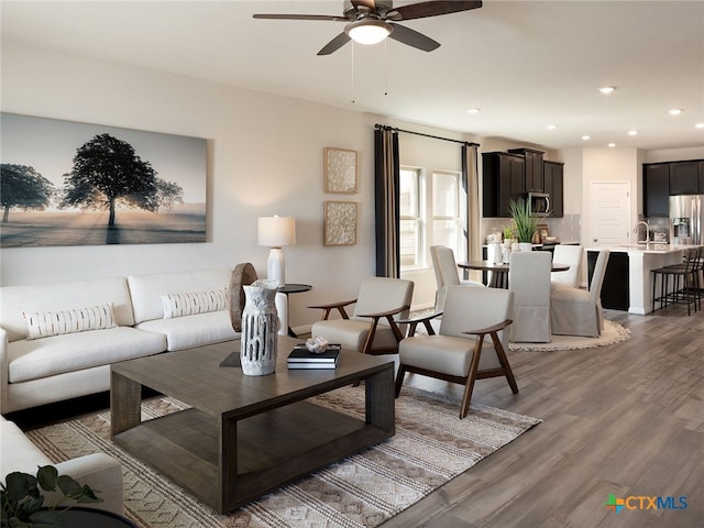 living room with hardwood / wood-style flooring, ceiling fan, and sink