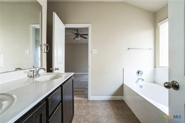 bathroom with ceiling fan, vanity, a tub to relax in, vaulted ceiling, and tile patterned floors