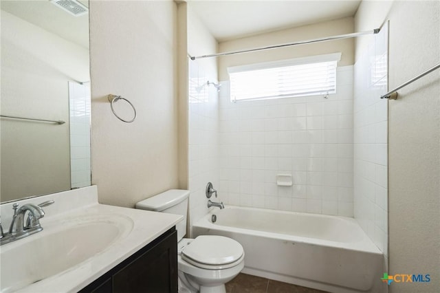 full bathroom with tile patterned flooring, tiled shower / bath, vanity, and toilet