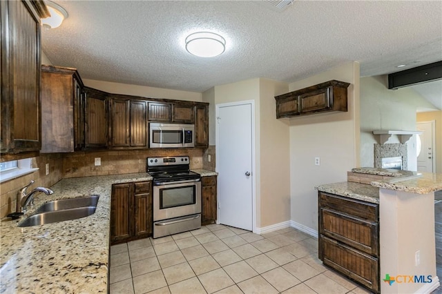 802 Antelope Trl, Temple, TX 76504 - kitchen featuring stainless steel appliances, a sink, decorative backsplash, dark brown cabinetry, and light stone countertops