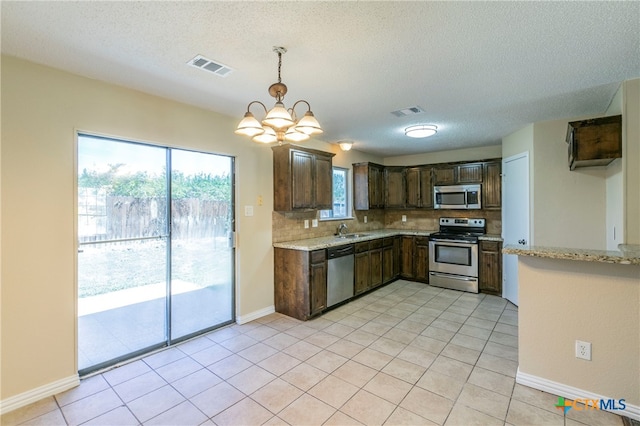 kitchen featuring stainless steel appliances, dark brown cabinetry, sink, backsplash, and light stone countertops