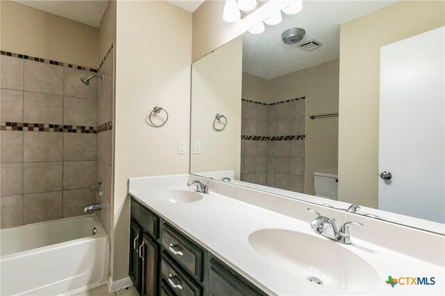 full bathroom with toilet, vanity, tiled shower / bath, and a textured ceiling