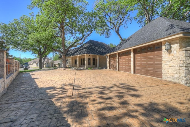133 Rio Azul, Seguin, TX 78155 - exterior space with a garage, driveway, stone siding, and roof with shingles