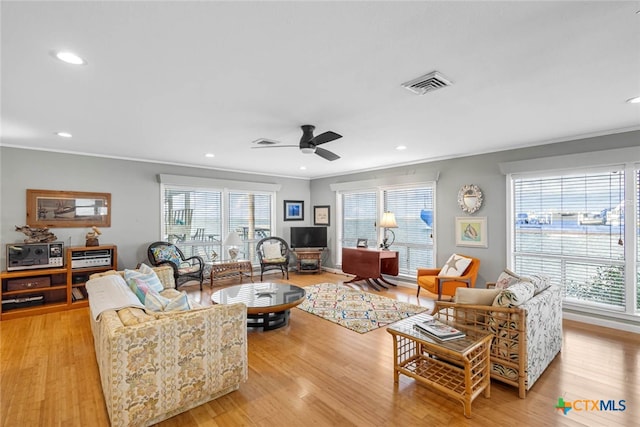 living room with ornamental molding, light wood-type flooring, and ceiling fan