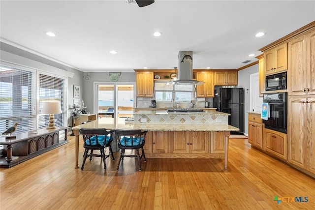 100 Bayshore Drive, Ingleside On The Bay, TX 78362 - kitchen featuring black appliances, island range hood, a kitchen island, a breakfast bar, and light wood-type flooring