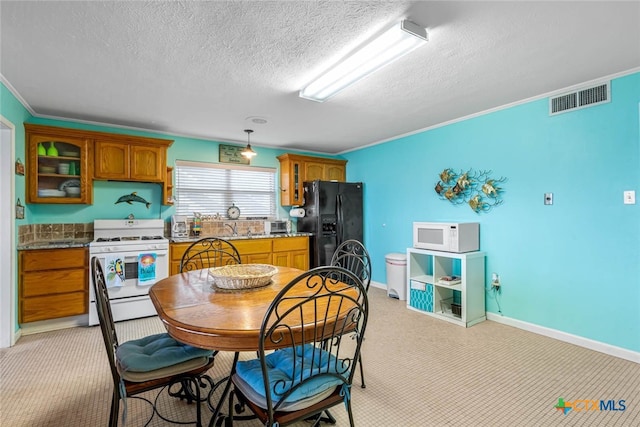 kitchen featuring light stone counters, a textured ceiling, white appliances, crown molding, and light colored carpet