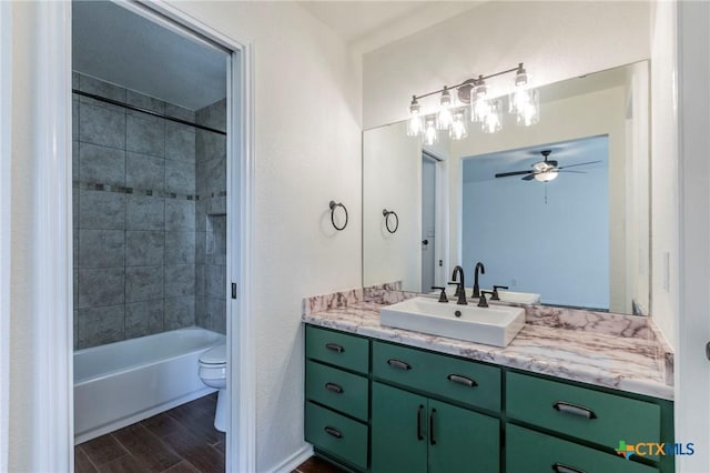 full bathroom with ceiling fan, vanity, tiled shower / bath combo, and toilet