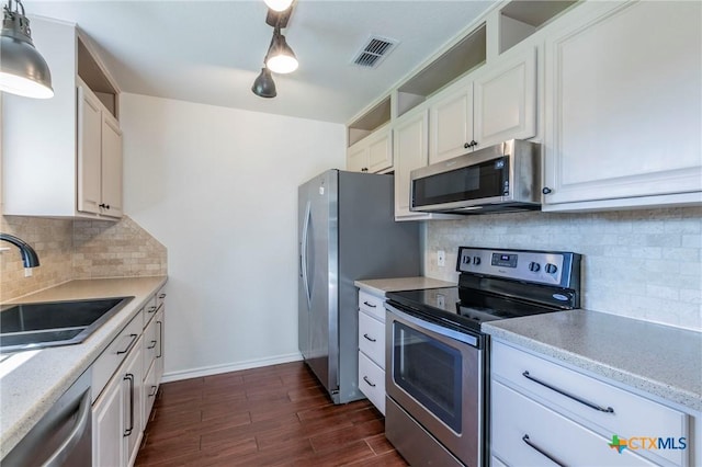 kitchen featuring pendant lighting, sink, tasteful backsplash, white cabinetry, and stainless steel appliances