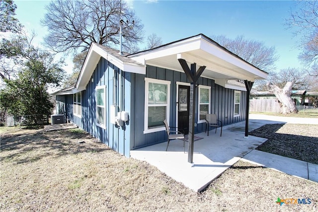 view of side of home with board and batten siding, a patio area, and fence