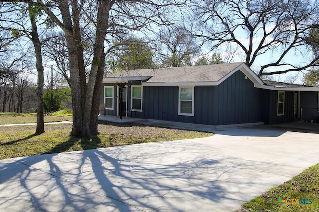 view of front of home featuring roof with shingles, board and batten siding, and concrete driveway