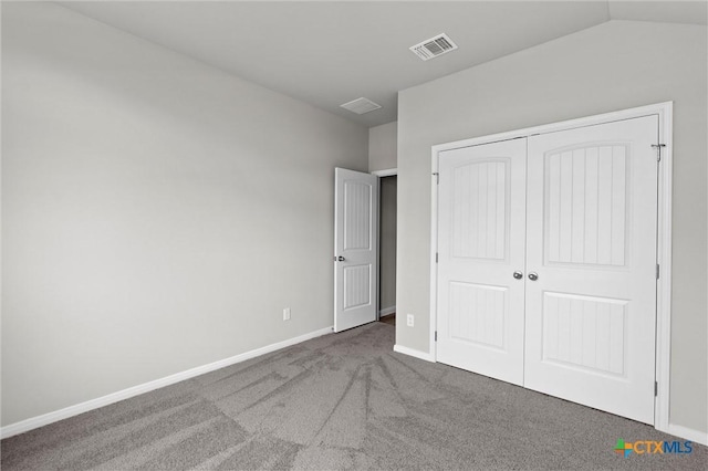 unfurnished bedroom with dark carpet, vaulted ceiling, and a closet