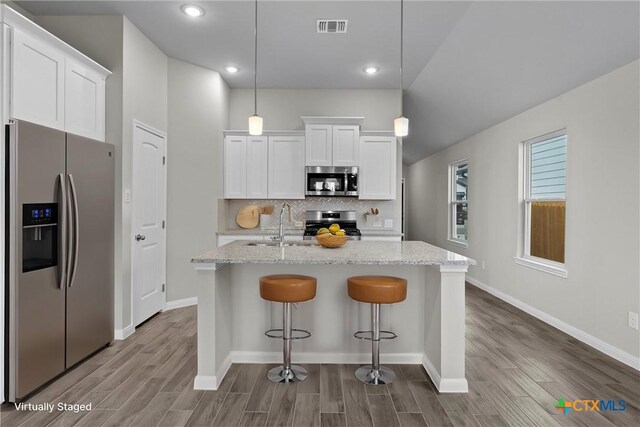 kitchen with light stone countertops, decorative light fixtures, white cabinetry, appliances with stainless steel finishes, and sink