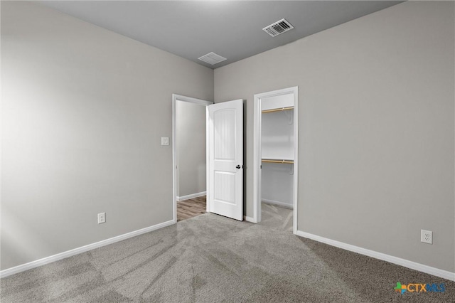 unfurnished bedroom featuring a walk in closet, carpet flooring, and a closet