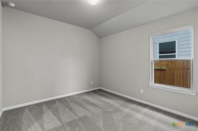 unfurnished room featuring lofted ceiling and carpet flooring