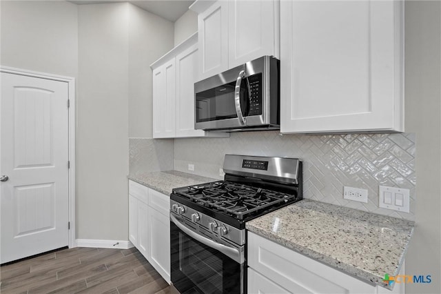 kitchen featuring light stone counters, decorative backsplash, stainless steel appliances, and white cabinets