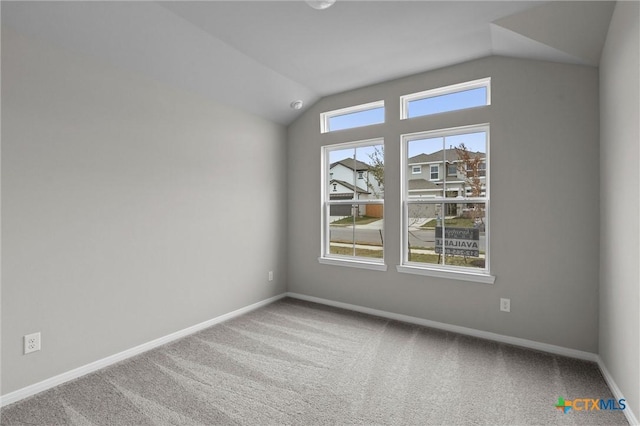 carpeted empty room with plenty of natural light and vaulted ceiling