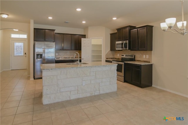 2521 Arno St, Harker Heights, TX 76548 - kitchen with appliances with stainless steel finishes, tasteful backsplash, dark brown cabinetry, a chandelier, and light stone counters