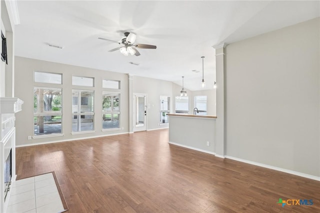 251 Las Brisas Blvd, Seguin, TX 78155 - unfurnished living room with a fireplace, ceiling fan, wood finished floors, and plenty of natural light