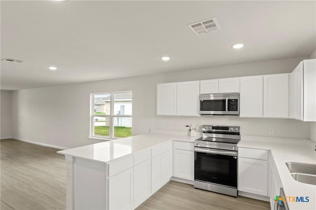 1007 Antelope Trl, Temple, TX 76504 - kitchen with stainless steel appliances, light wood-style flooring, a peninsula, white cabinets, and open floor plan