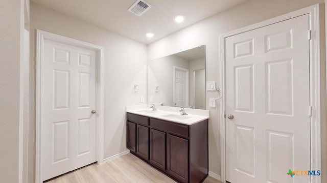 full bathroom with double vanity, wood finished floors, a sink, and visible vents