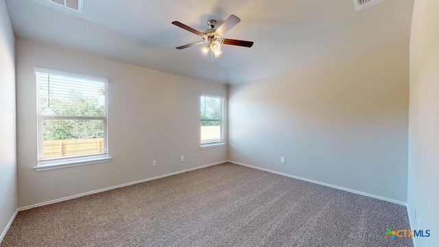 carpeted empty room featuring ceiling fan, visible vents, and baseboards