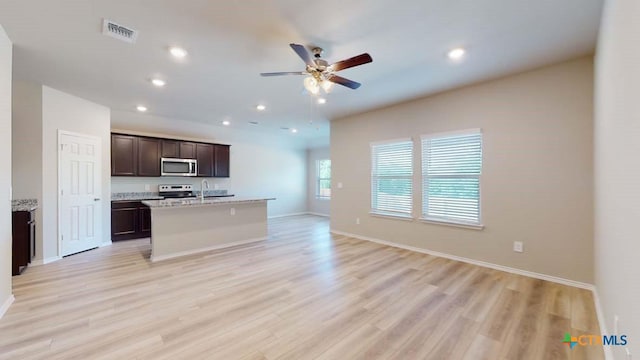 kitchen with visible vents, light wood-style flooring, appliances with stainless steel finishes, open floor plan, and a kitchen island with sink