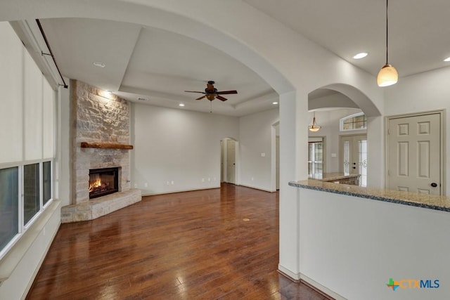 living room with a raised ceiling, dark wood-type flooring, and a fireplace