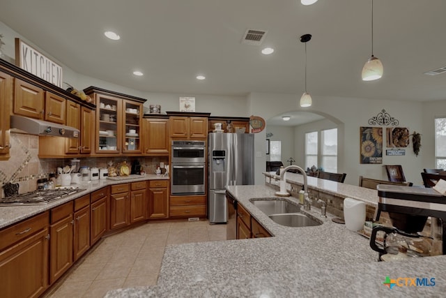 kitchen with hanging light fixtures, appliances with stainless steel finishes, sink, and decorative backsplash