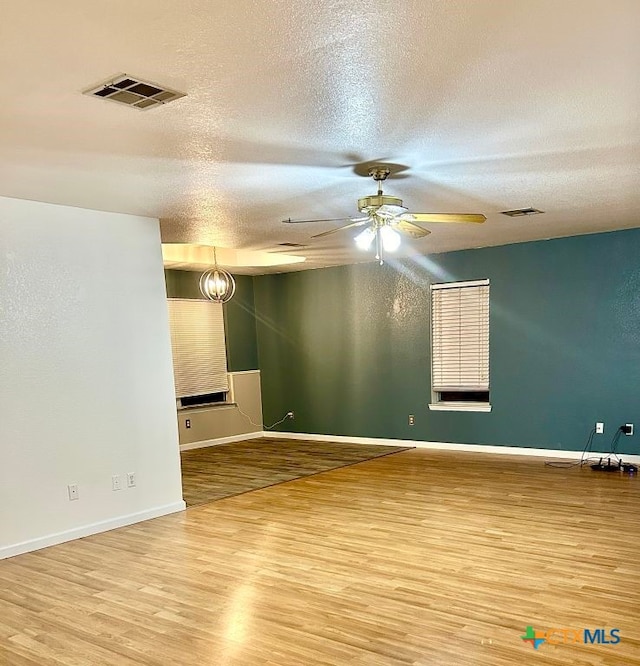 empty room with ceiling fan, wood-type flooring, and a textured ceiling