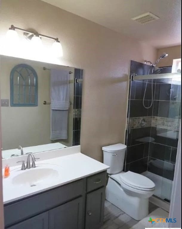 bathroom with toilet, vanity, and a shower with door