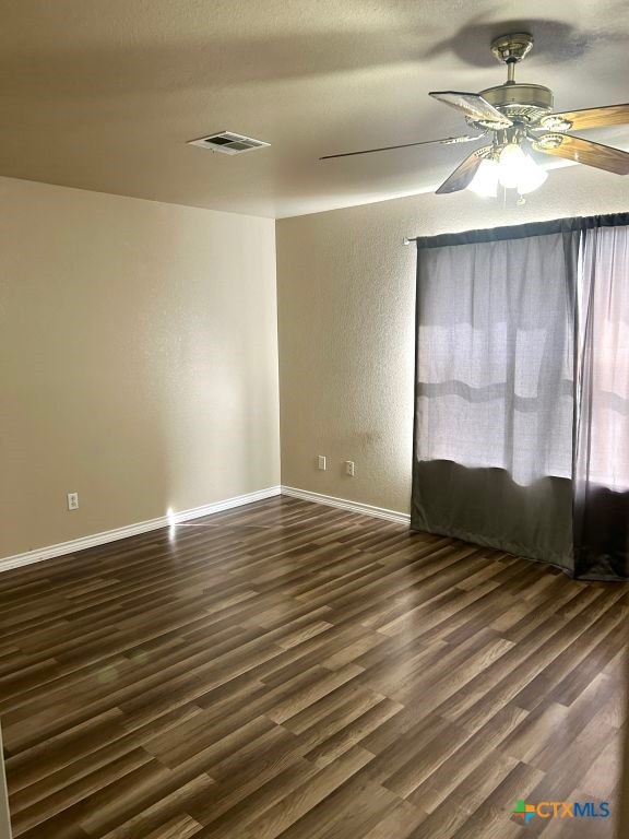 spare room featuring dark wood-type flooring, a textured ceiling, and ceiling fan