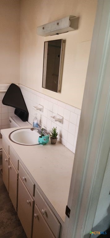 bathroom featuring vanity, toilet, and tile walls