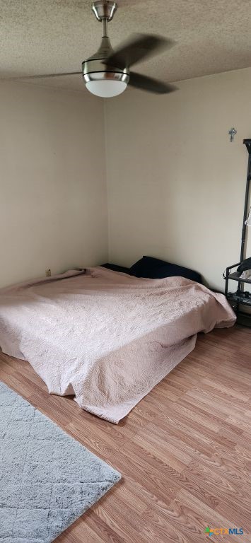 unfurnished bedroom featuring light hardwood / wood-style flooring, a textured ceiling, and ceiling fan