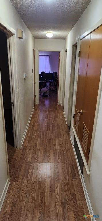 corridor featuring a textured ceiling and dark hardwood / wood-style floors