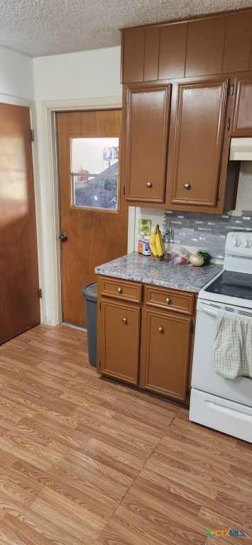 kitchen with white electric stove, light wood-type flooring, a textured ceiling, and exhaust hood