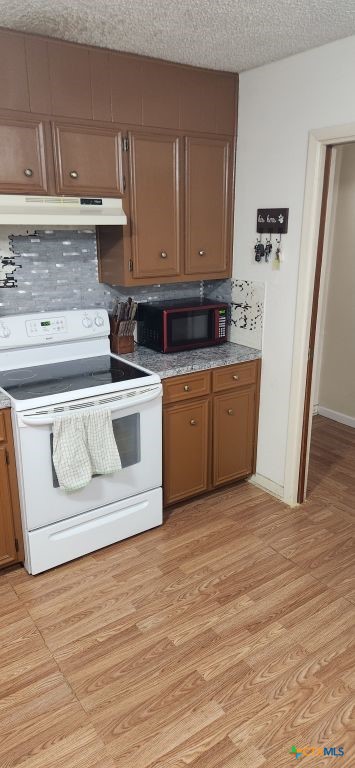 kitchen featuring light hardwood / wood-style floors, a textured ceiling, tasteful backsplash, and white range with electric stovetop