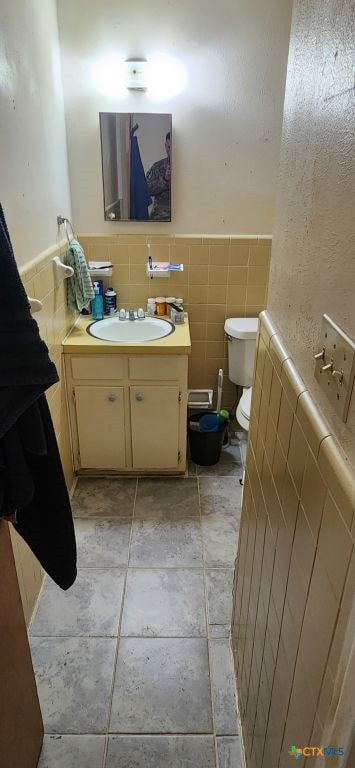 bathroom featuring vanity, toilet, and tile walls