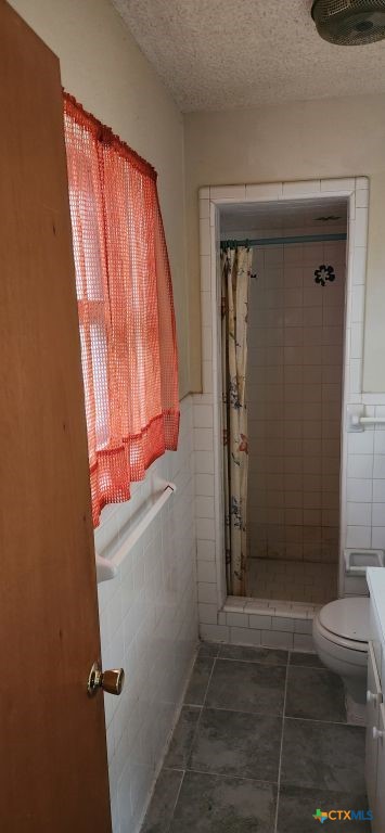 bathroom with tile walls, curtained shower, tile patterned flooring, and vanity