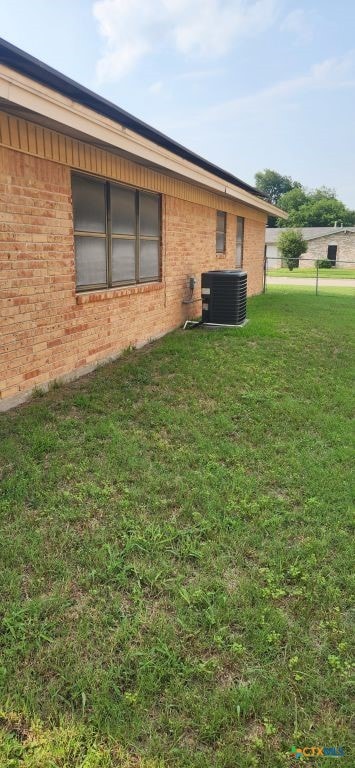 view of side of home featuring a lawn and cooling unit