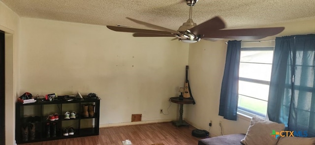 living room with hardwood / wood-style floors, ceiling fan, and a textured ceiling