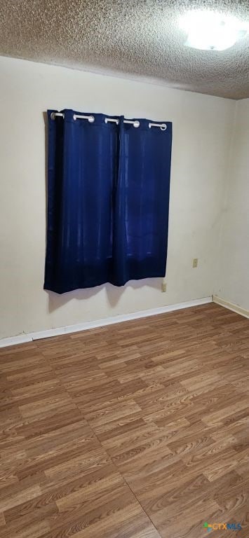 spare room with hardwood / wood-style floors and a textured ceiling