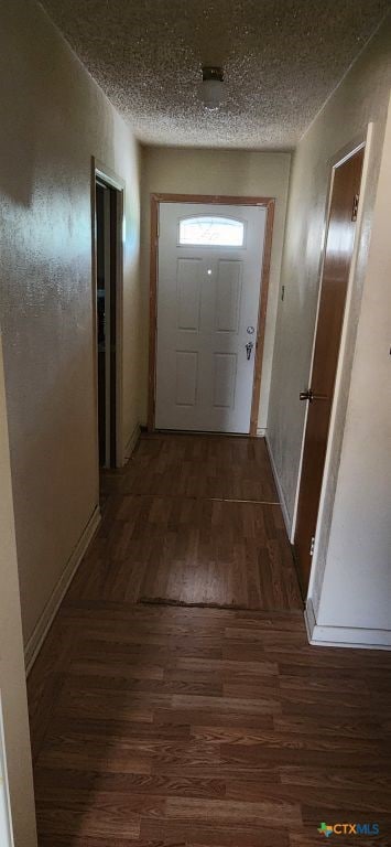 corridor with a textured ceiling and dark hardwood / wood-style floors