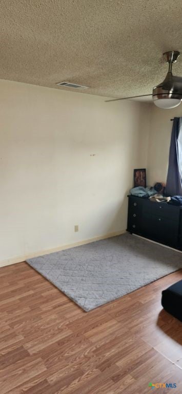 empty room with a textured ceiling, hardwood / wood-style flooring, and ceiling fan