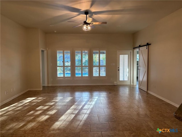 empty room with ceiling fan and a barn door