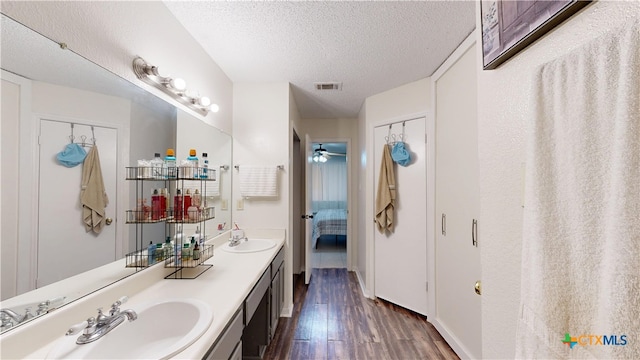 ensuite bathroom with a textured ceiling, wood finished floors, ensuite bathroom, and a sink
