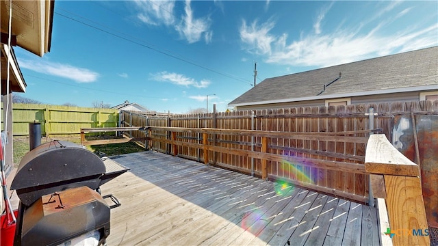 wooden terrace with a fenced backyard and a grill