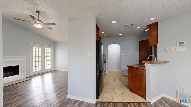 kitchen with arched walkways, a textured ceiling, visible vents, and a fireplace