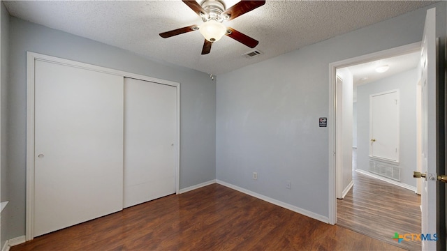 unfurnished bedroom featuring wood finished floors, a textured ceiling, a closet, baseboards, and visible vents